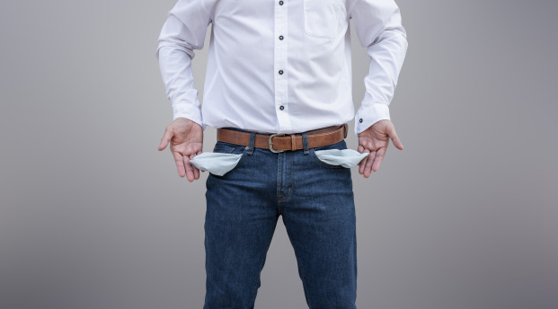 homem de camisa branca e calça jeans mostrando os bolsos vazios