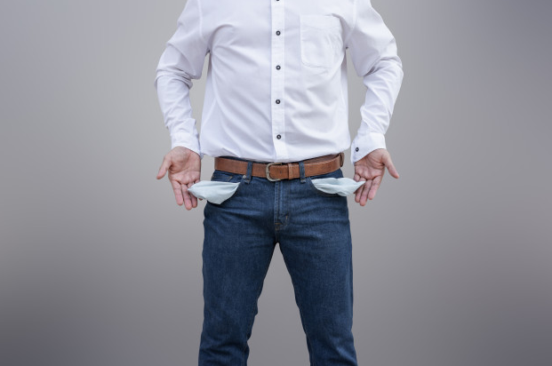 homem de camisa branca e calça jeans mostrando os bolsos vazios