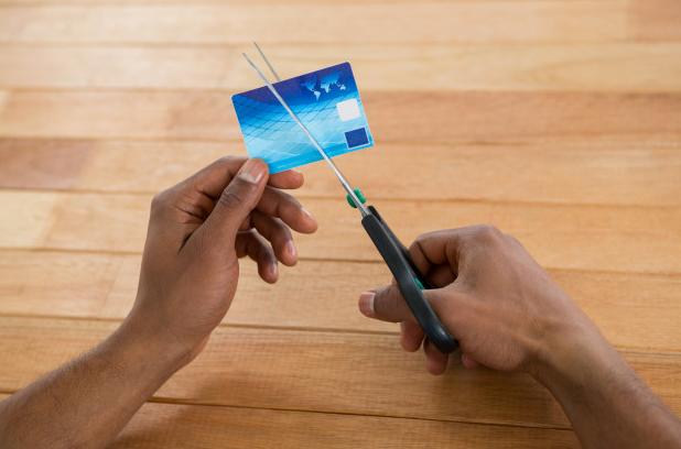 imagem ampliada de homem usando uma tesoura para cortar cartão de crédito cancelado