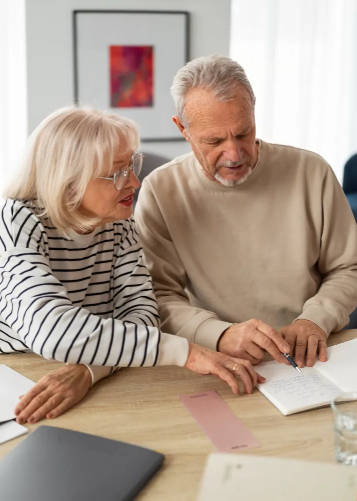casal de idosos sentados à messa escrevendo em caderneta - como saber quantas parcelas faltam do empréstimo consignado INSS
