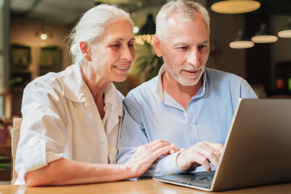 casal-de-meia-idade-sentados-a-mesa-com-laptop-empréstimo consignado inss online