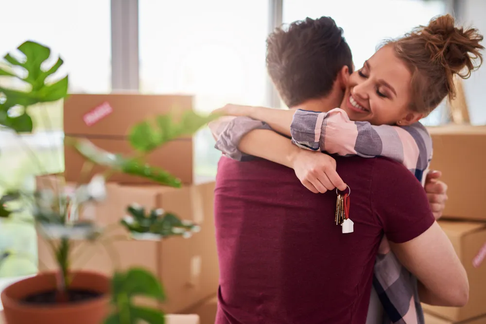 casal se abraçando com a chave da casa nova na mão - consórcio imobiliário