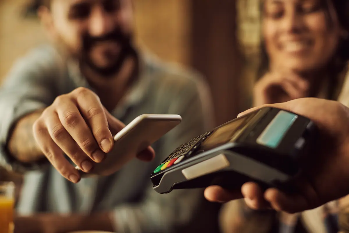 comprar à vista ou parcelado? Casal decidindo a melhor forma de pagamento em uma maquininha de cartão