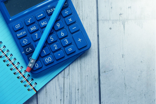calculadora, lápis e caderno azuis em cima de uma mesa cinza