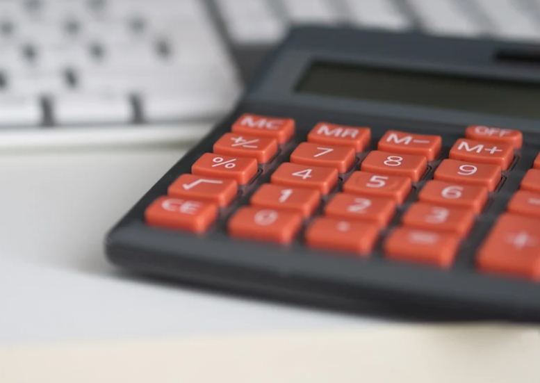 calculadora cinza com teclado vermelho em cima de uma mesa com teclado branco