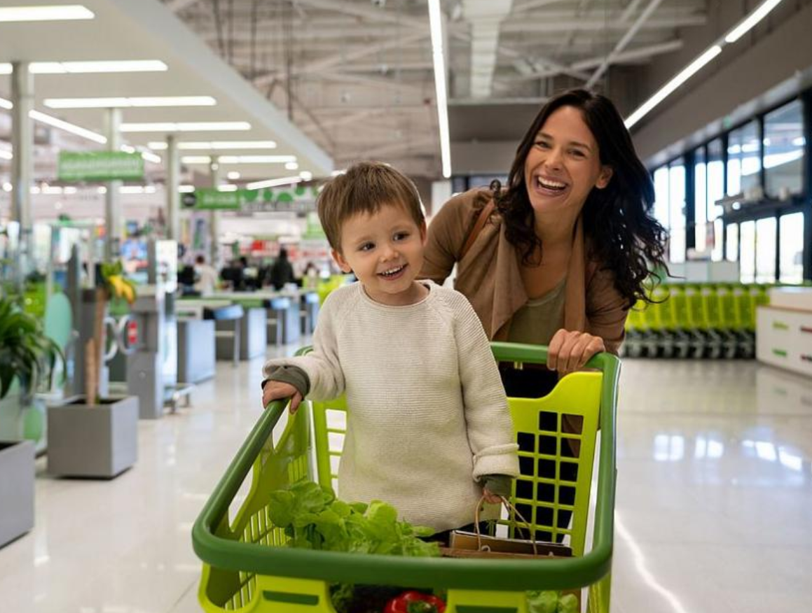 mãe brincando com o filho que encontra-se dentro do carrinho de super mercado enquanto fazem compras