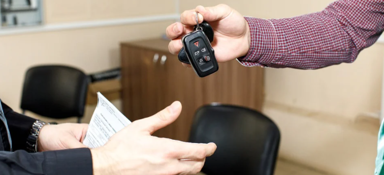 imagem ampliada de uma pessoa com papéis na mão recebendo uma chave de carro de outra pessoa