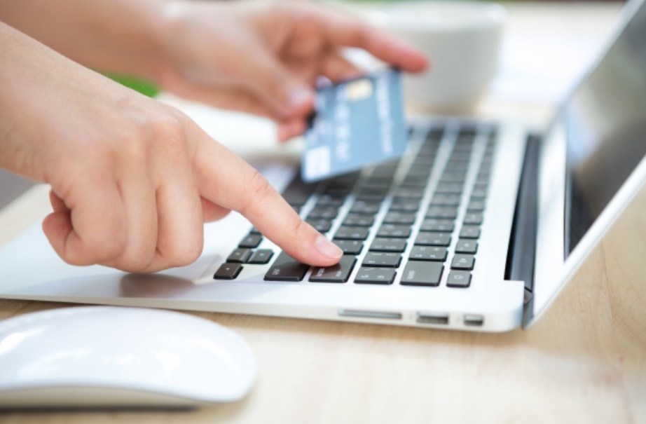 imagem ampliada de uma mulher segurando um cartão de crédito e digitando em um laptop