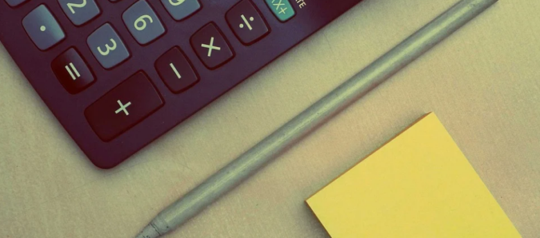 mesa com calculadora, caneta e post-it amarelo