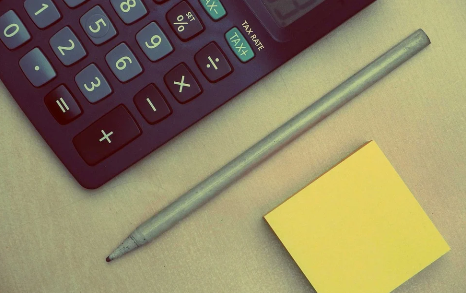 mesa com calculadora, caneta e post-it amarelo