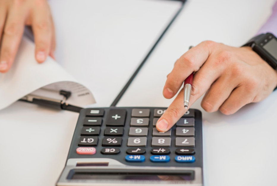 imagem aproximada de um homem de camisa fazendo contas em uma calculadora