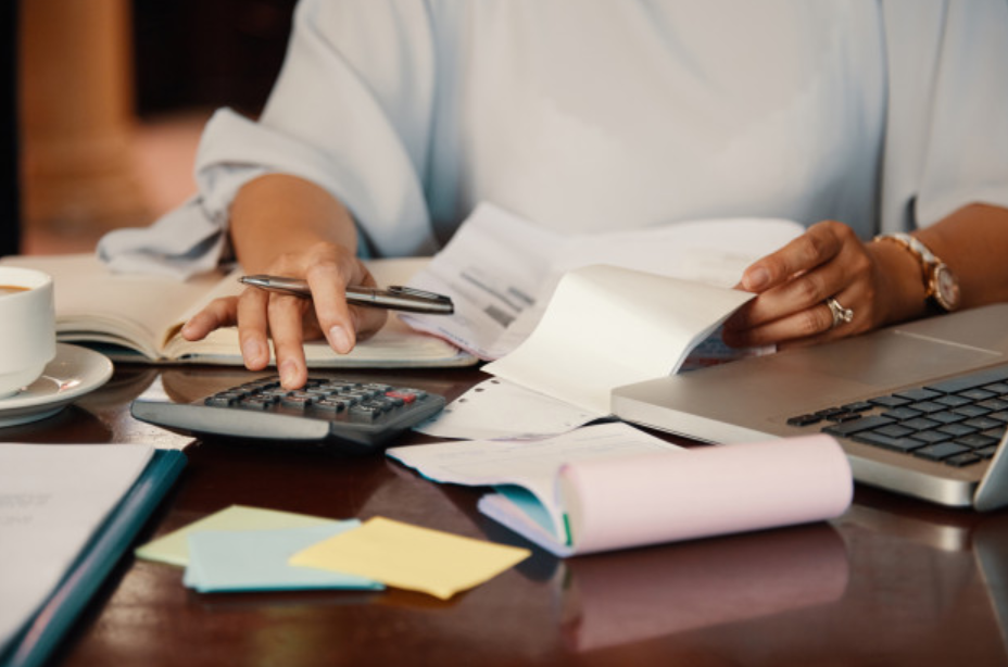 imagem ampliada de uma mulher fazendo cálculos e analisando contas fixas para pagar