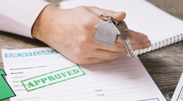 imagem de mão masculina segurando molho de chaves em cima de um documento aprovado