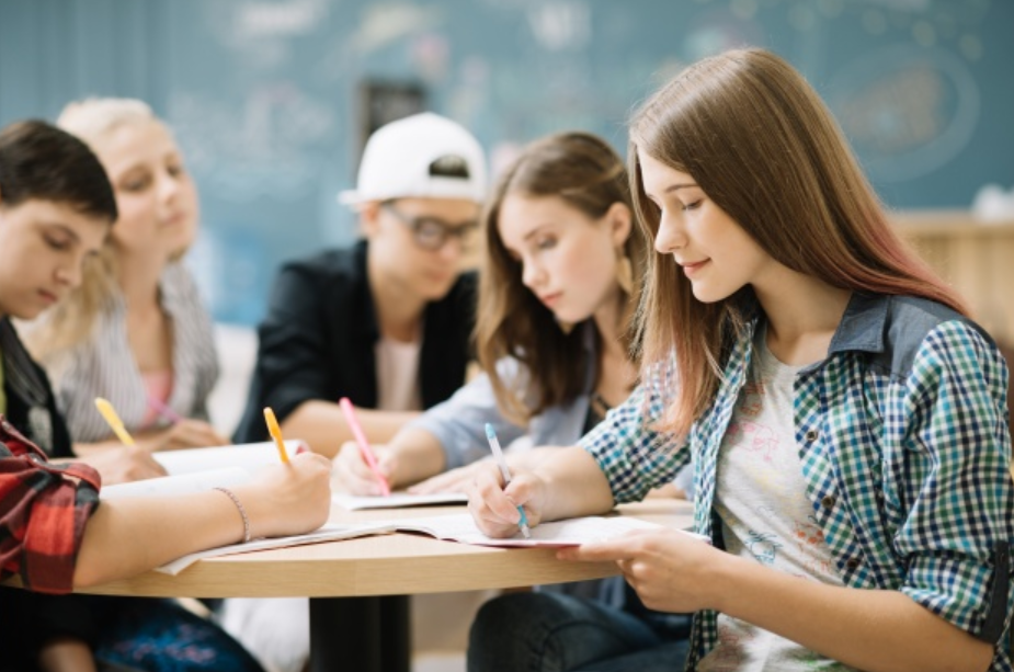 imagem de jovens sentados a uma mesa estudando e anotando sobre educação financeira