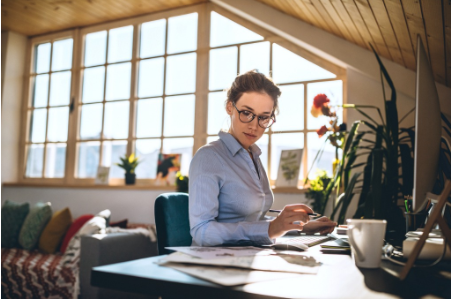 mulher de caisa azul e óculos usando seu computador no home office