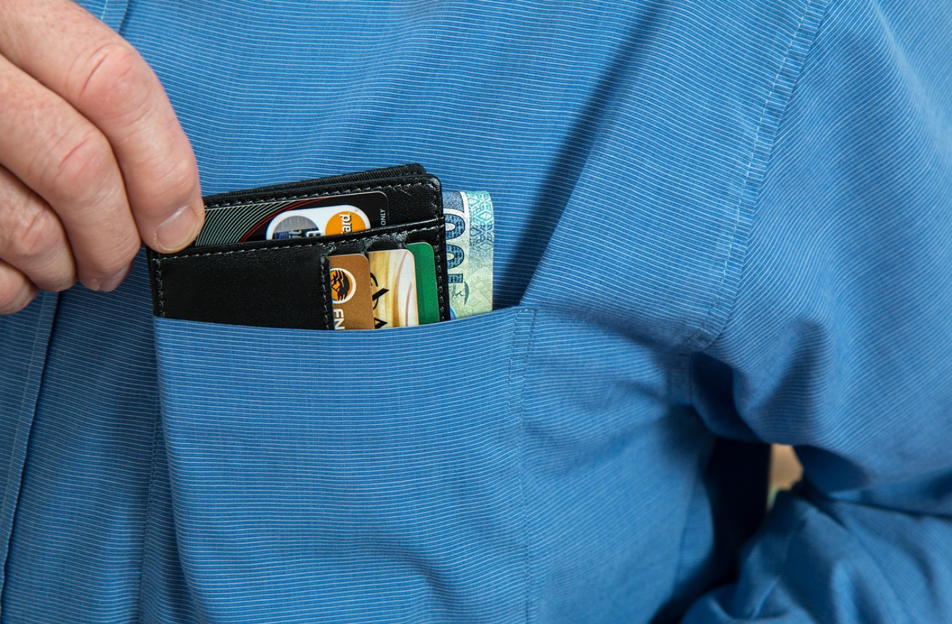 homem de camisa azul com sua carteira dentro do bolso de sua camisa