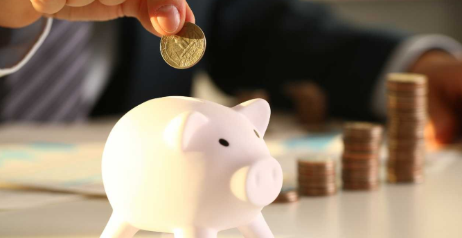 imagem ampliada de uma pessoa colocando dinheiro em um cofre com formato de porco
