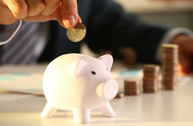 imagem ampliada de uma pessoa colocando dinheiro em um cofre com formato de porco