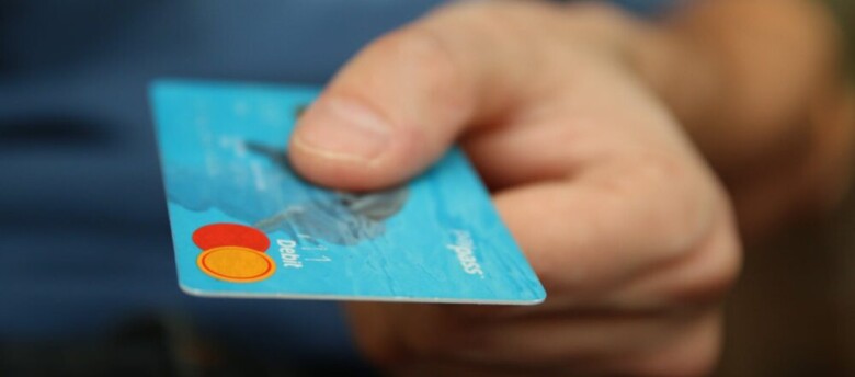 imagem ampliada de um homem segurando um cartão de crédito azul