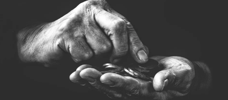 Foto artística com close em mãos que contam poucas moedas. A foto está em preto e branco