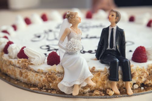 bonecos de noiva e noivo em cima de um bolo de casamento
