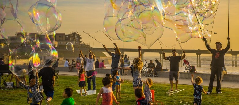 Crianças e adultos festejando em um parque com bolhas de sabão