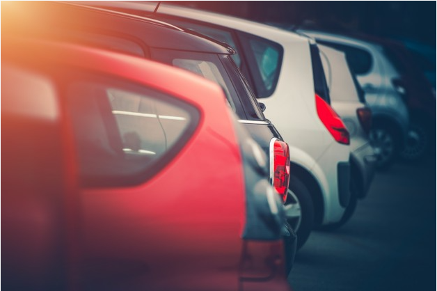 carros nas cores vermelha, cinza e branca enfileirados em um estacionamento
