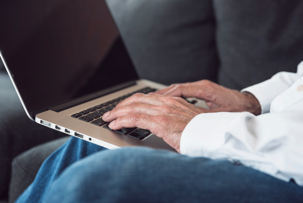 foto das mãos de senhor de idade mexendo no notebook enquanto sentado - 14 salario aposentados