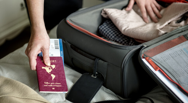 imagem ampliada de uma pessoa organizando uma mala de viagem e segurando um passaporte