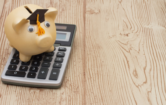 imagem de uma calculadora sobre uma mesa com um cofre de porco usando um chapéu em cima