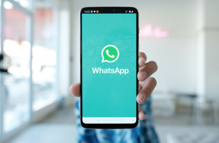 pessoa segurando celular touchscreen com o logo da rede whatsapp na tela