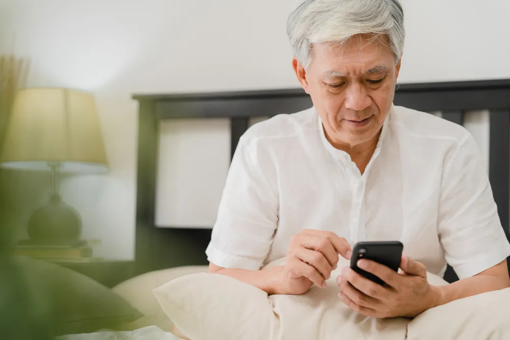 homem de maior idade sentado em casa mexendo no celular - qual a taxa de juros para aposentados do inss