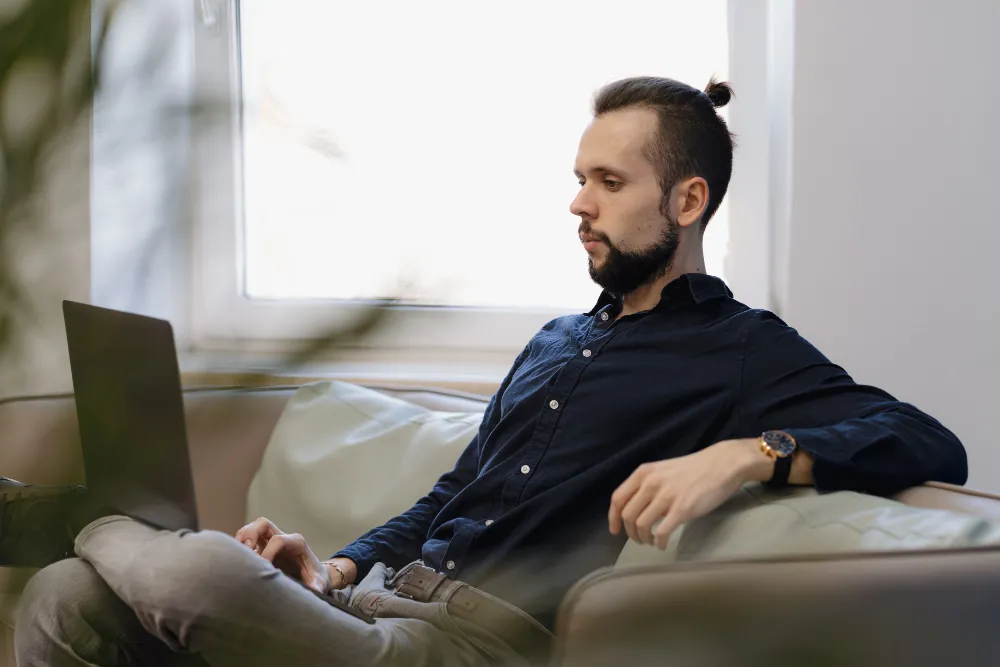 homem de negócios sentado no sofá mexendo no computador - quanto a poupança rende hoje