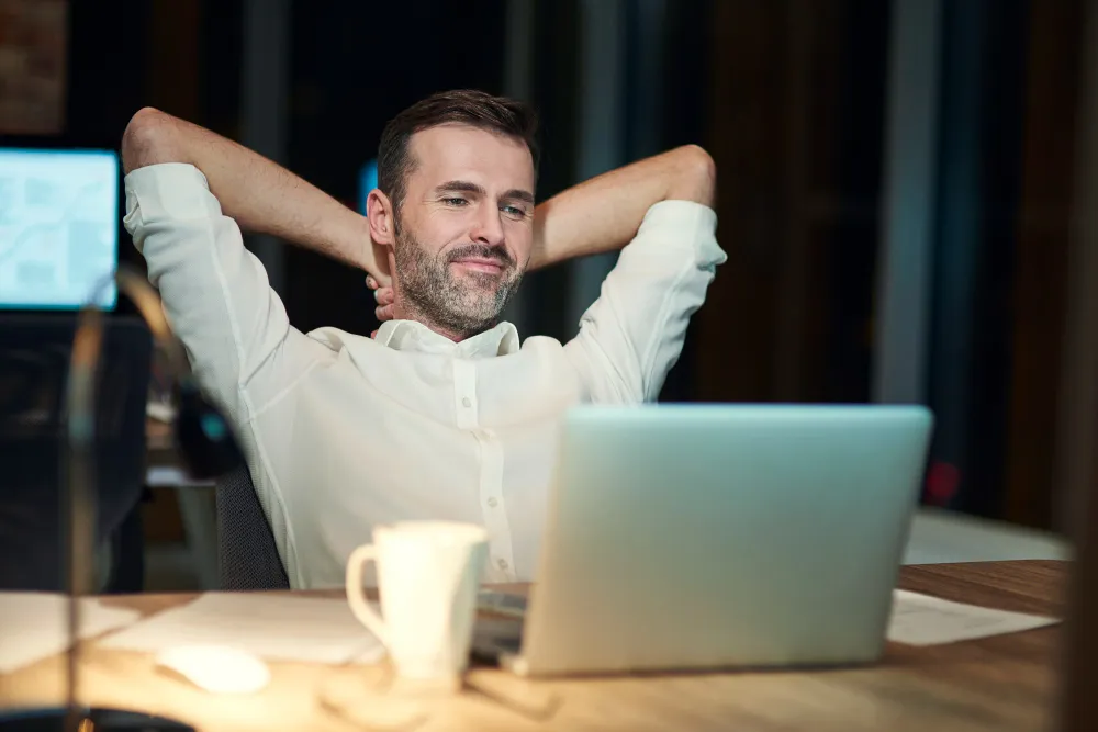 homem relaxado e sorridente mexendo no computador de casa - empréstimo com garantia do fgts