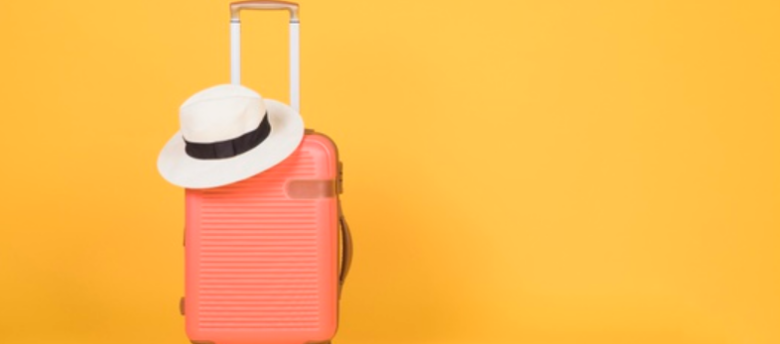 imagem de uma mala de viagens com um chapéu branco em cima em frente de um fundo laranja