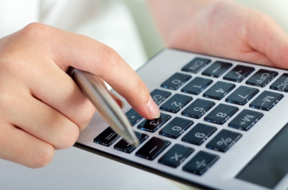 imagem ampliada de uma pessoa segurando uma caneta e fazendo contas em uma calculadora