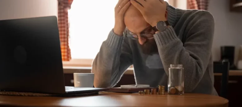 Homem preocupado com Como proteger dinheiro de golpes financeiros e contas abertas, representando atenção contra golpes financeiros e fraudes em 2026.