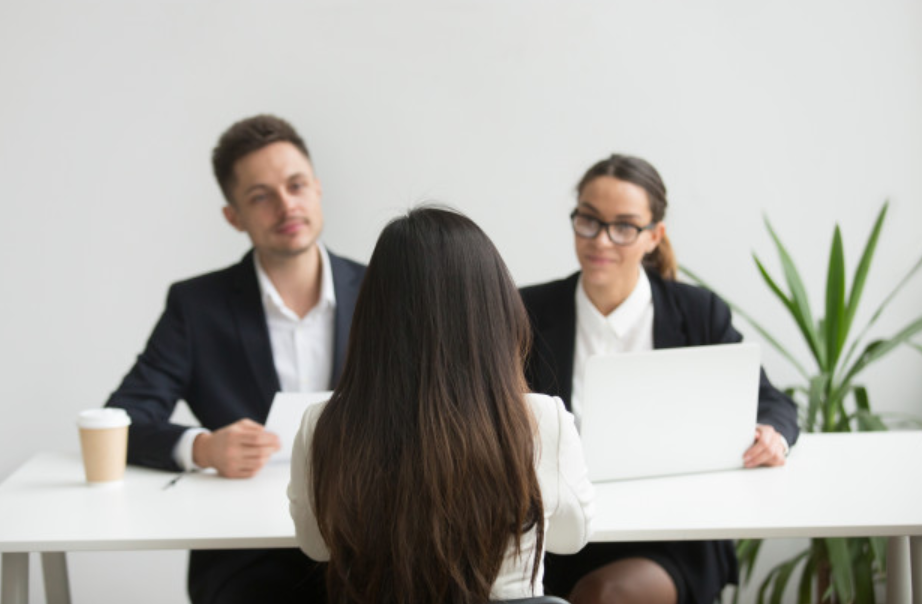 imagem de uma mesa com três pessoas realizando uma entrevista para mudar de emprego