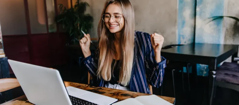 mulher comemorando em frente ao computador - empréstimo com garantia de salário