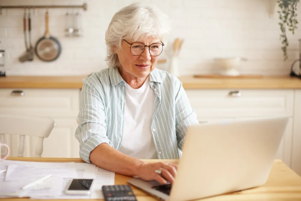 mulher de idade mexendo no computador em casa - dívida ativa impede aposentadoria
