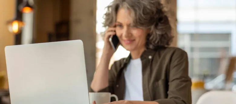 mulher de idade no computador falando no celular - como quitar um empréstimo consignado inss