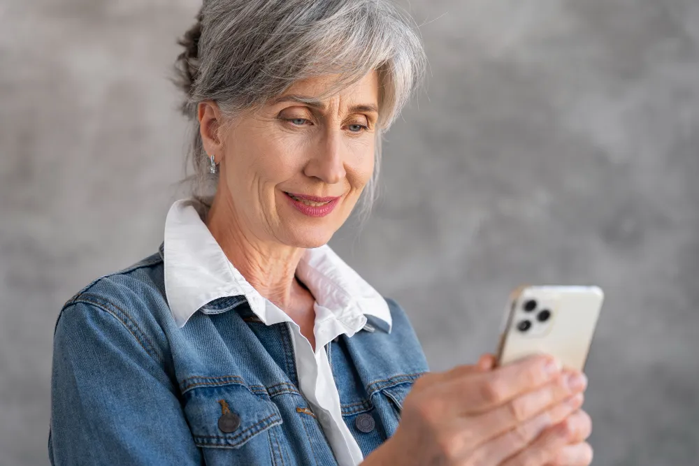 mulher idosa sorrindo enquanto usa o celular - empréstimo consignado estourou a margem