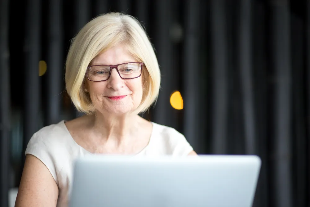 mulher de idade usando oculos no computador - ate quantos anos aposentado pode fazer emprestimo