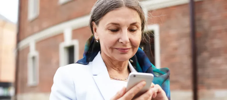mulher de maior idade ao ar livre mexendo no celular - qual a taxa de juros para aposentados do inss