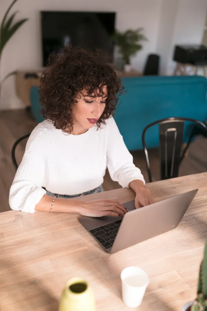 mulher sentada à mesa mexendo no notebook - cpf negativado