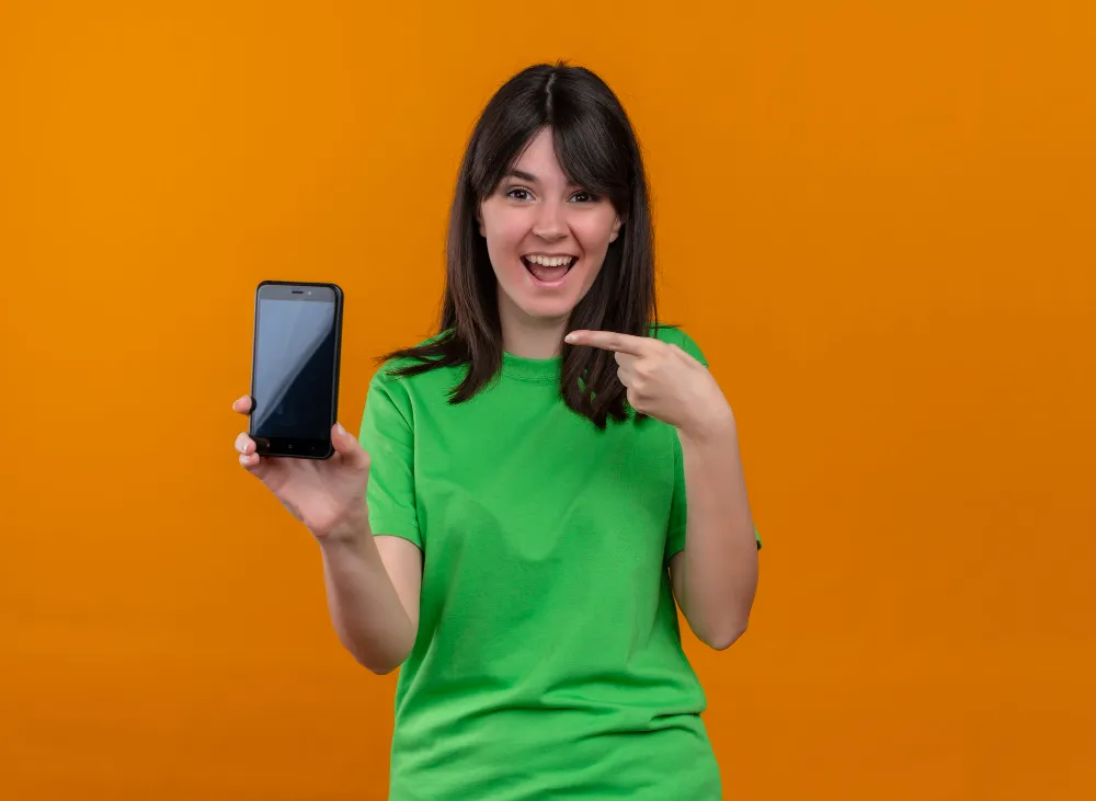 mulher sorridente apontando para o aparelho celular - empréstimo com garantia de celular para negativado