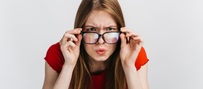 imagem de uma mulher de óculos com olhar curioso de costas para um fundo branco