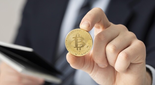 homem de terno segurando moeda com o símbolo do Bitcoin