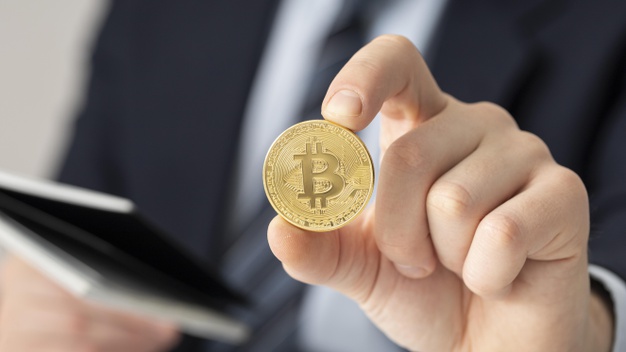 homem de terno segurando moeda com o símbolo do Bitcoin