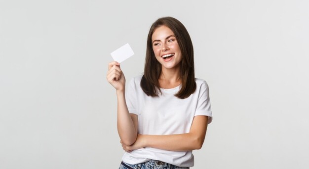 mulher de jeans azul e camiseta branca segura um cartão e sorri